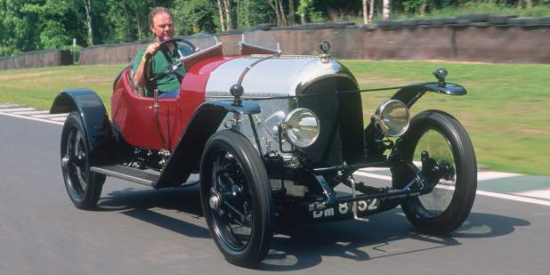A red Bentley 3-Litre from the 1920s being driven outdoors | Bentley Motors
