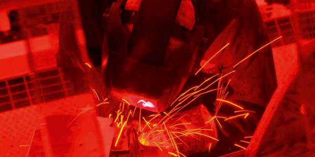 Red coloured image of a Bentley engineer welding metal | Bentley Motors